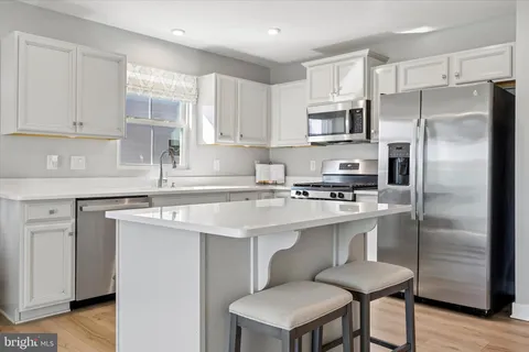 a kitchen with stainless steel appliances a sink a stove a refrigerator cabinets and a window