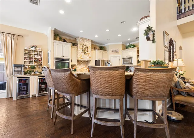 a dining room with stainless steel appliances granite countertop a table chairs and a wooden floor