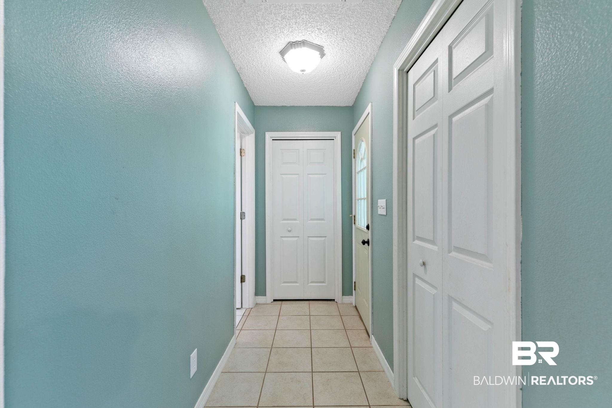 20219 Greek Cemetery Road Robertsdale, AL 36567 - Photo 30 of 41 Hallway featuring tile flooring, light blue walls, and multiple panel doors