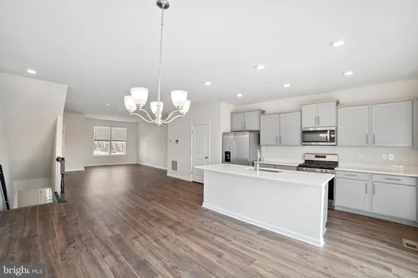 a kitchen with kitchen island granite countertop a sink a counter space stainless steel appliances and cabinets