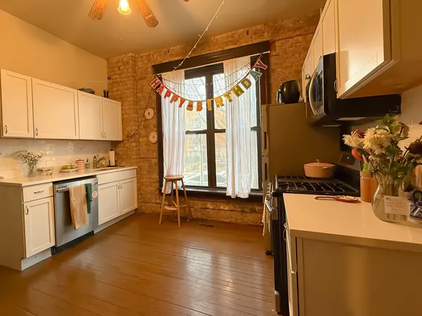 a kitchen with a sink appliances cabinets and a large window
