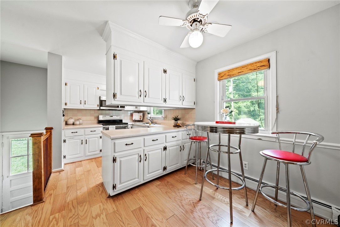 4001 Croatan Road Richmond, VA 23235 - Photo 6 of 25 a kitchen with stainless steel appliances granite countertop white cabinets a sink dishwasher a dining table and chairs with wooden floor