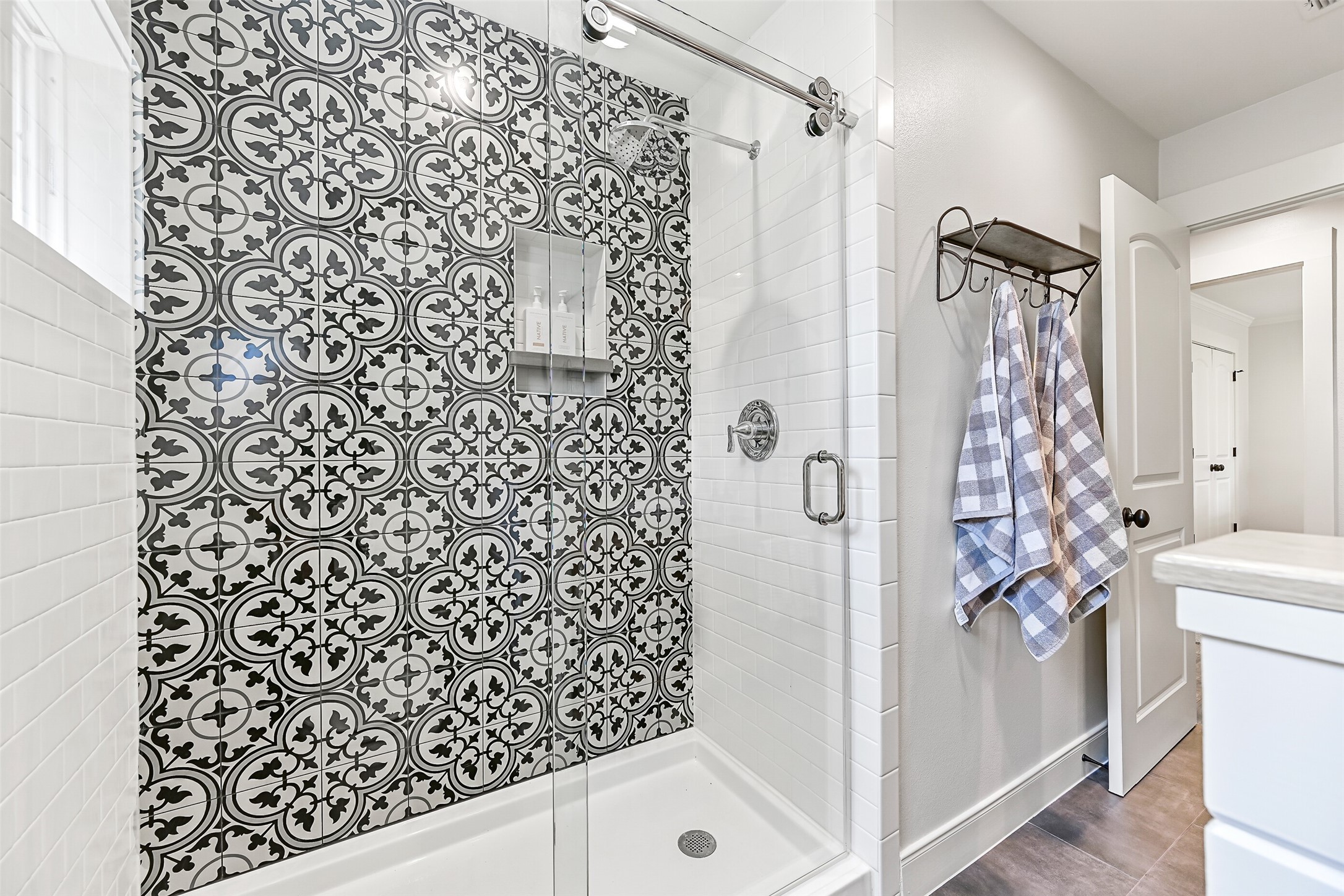 3042 Poskey Road Anahuac, TX 77514 - Photo 24 of 50 Luxurious shower with striking black and white tile accent, glass door, and chrome fixtures. Features light grey walls, a sleek white vanity, and a convenient towel rack.