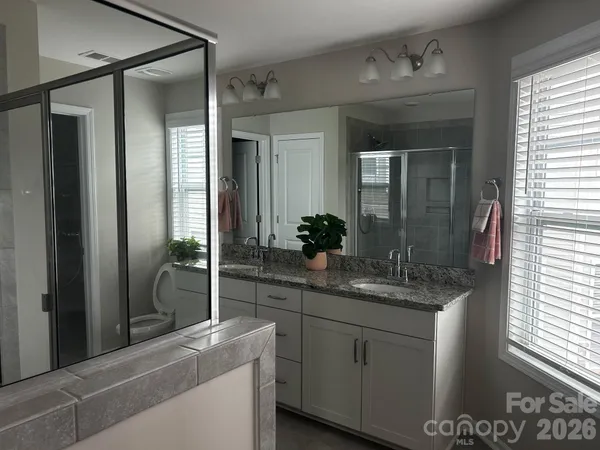 a bathroom with a granite countertop sink a mirror and a shower