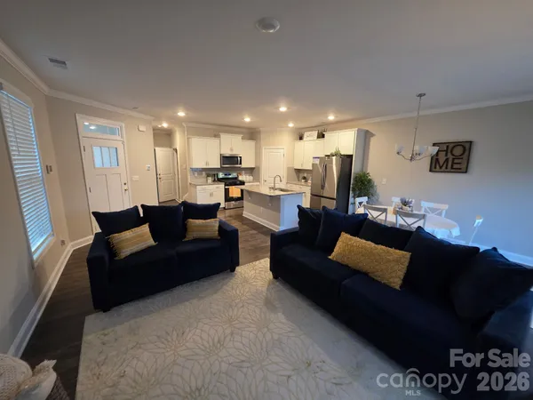 a living room with furniture a rug and kitchen view