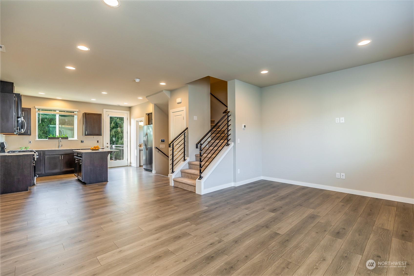 19308 35th Drive Southeast, Unit D Bothell, WA 98012 - Photo 7 of 32 a view of an empty room with wooden floor and a kitchen