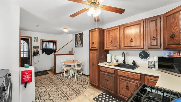 a open kitchen with stainless steel appliances granite countertop a refrigerator a sink dishwasher a dining table and chairs with wooden floor