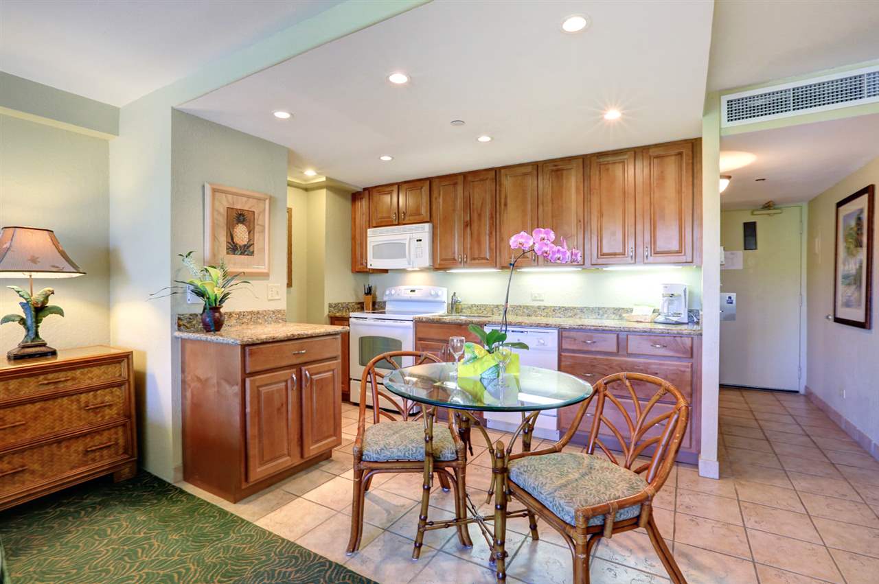 3445 Lower Honoapiilani Road, Unit 336 Lahaina, HI 96761 - Photo 9 of 22 a kitchen with a dining table chairs and a refrigerator