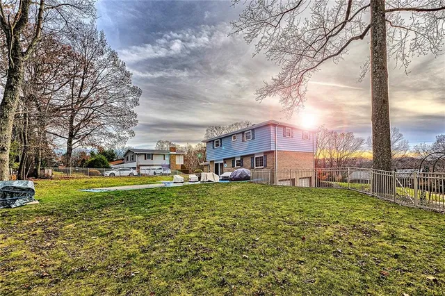 a view of a house with a big yard and large trees
