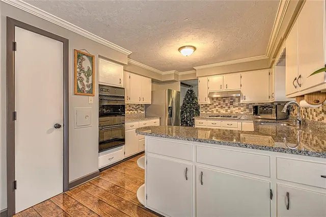 a kitchen with stainless steel appliances kitchen island granite countertop a refrigerator and cabinets