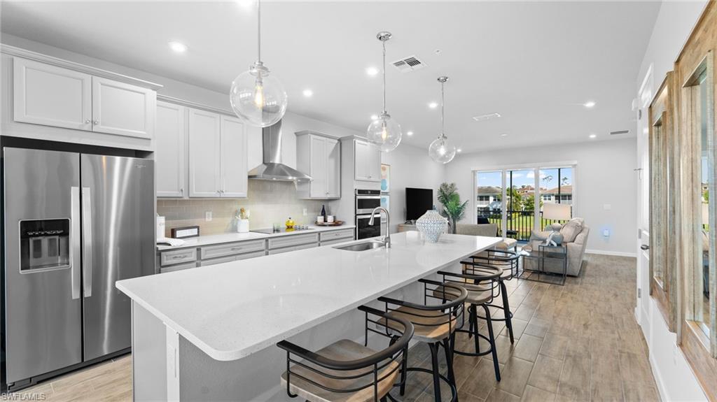 4601 Arboretum Circle, Unit 202 Naples, FL 34112 - Photo 7 of 37 a kitchen with stainless steel appliances kitchen island a wooden floor and white cabinets