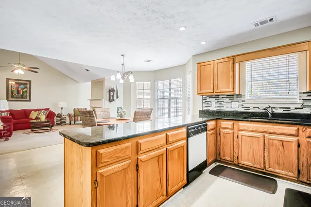 a kitchen with stainless steel appliances granite countertop sink window and white cabinets