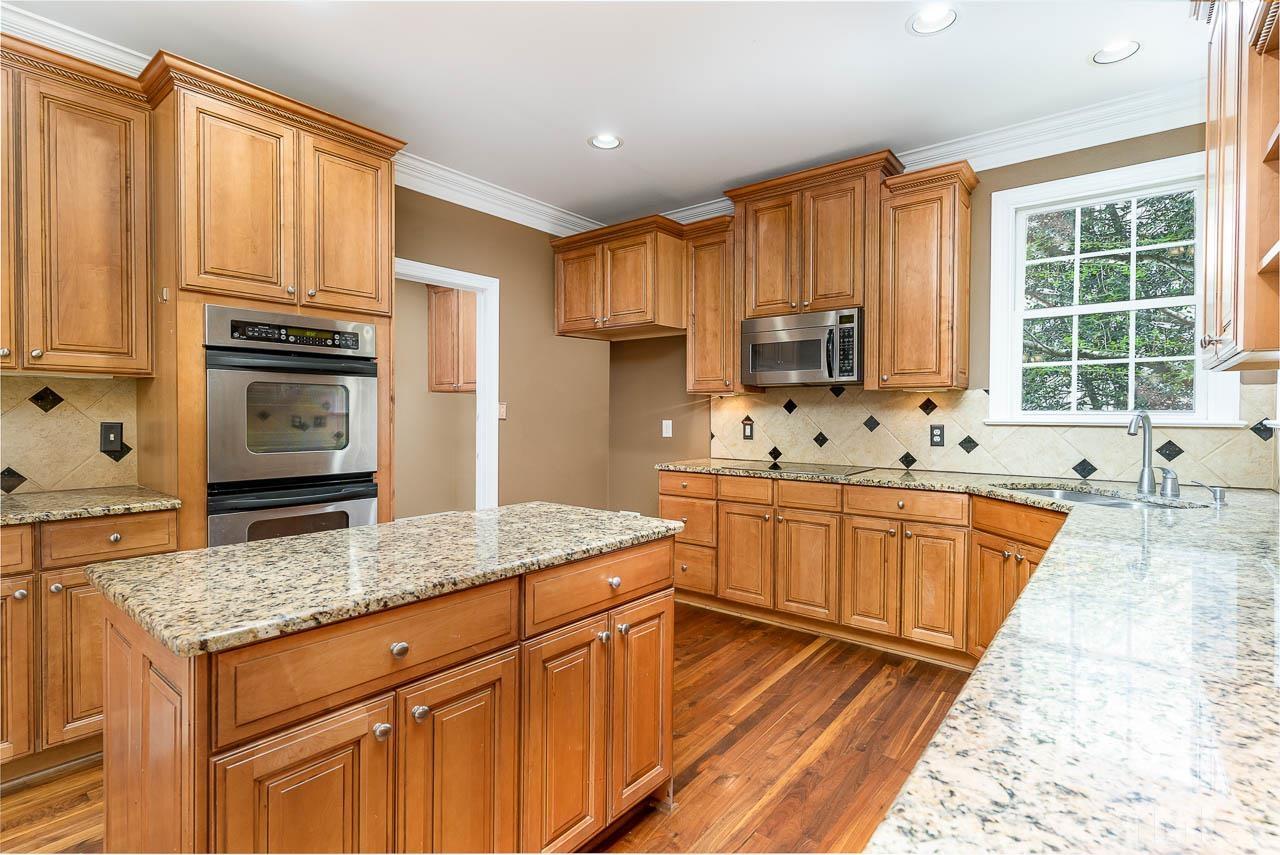 1317 Wynncrest Court Raleigh, NC 27603 - Photo 10 of 35 a kitchen with stainless steel appliances granite countertop a stove a sink dishwasher and a refrigerator with wooden cabinets