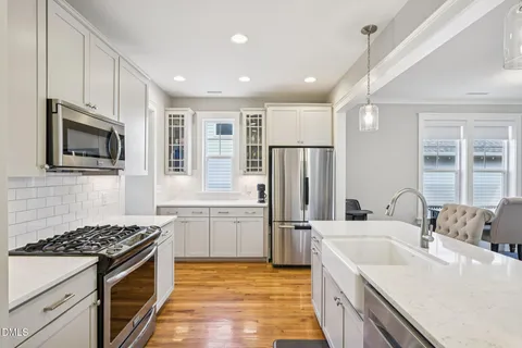 a kitchen with stainless steel appliances granite countertop a stove a sink dishwasher a refrigerator and a microwave with wooden floor