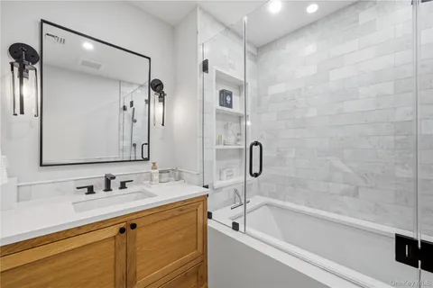 a bathroom with a granite countertop sink a mirror a bathtub and shower