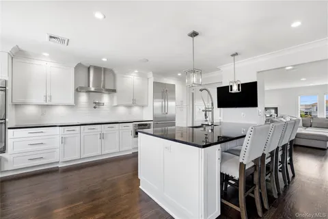 a kitchen with stainless steel appliances kitchen island granite countertop a stove and a wooden floor