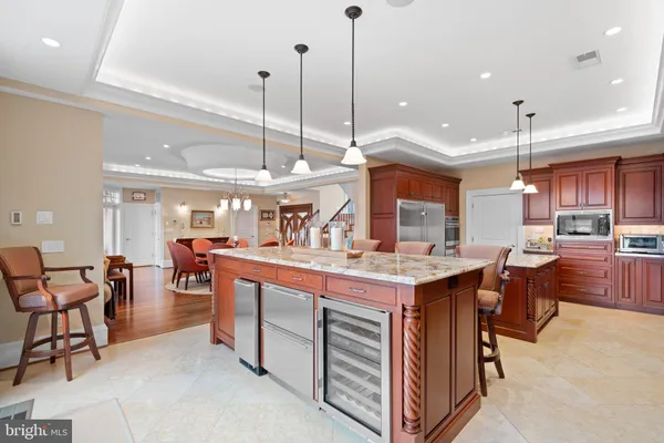 a front view of a kitchen with stainless steel appliances granite countertop a stove and a microwave
