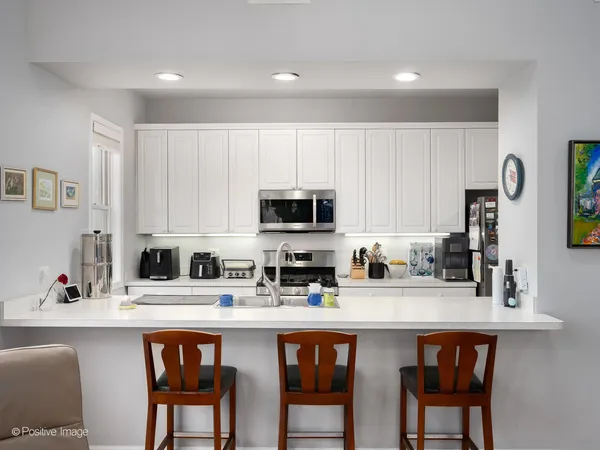 a kitchen with stainless steel appliances a sink a stove a table and chairs