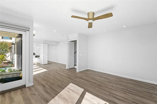 a view of a livingroom with wooden floor a ceiling fan and window