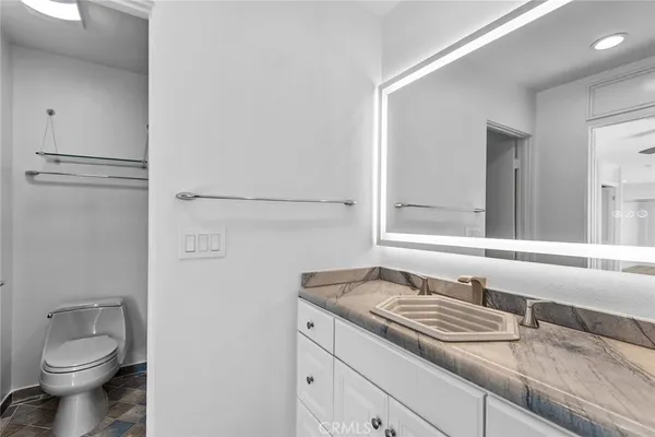 a bathroom with a granite countertop sink and a toilet