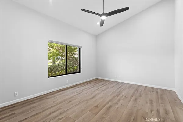 an empty room with wooden floor chandelier fan and windows