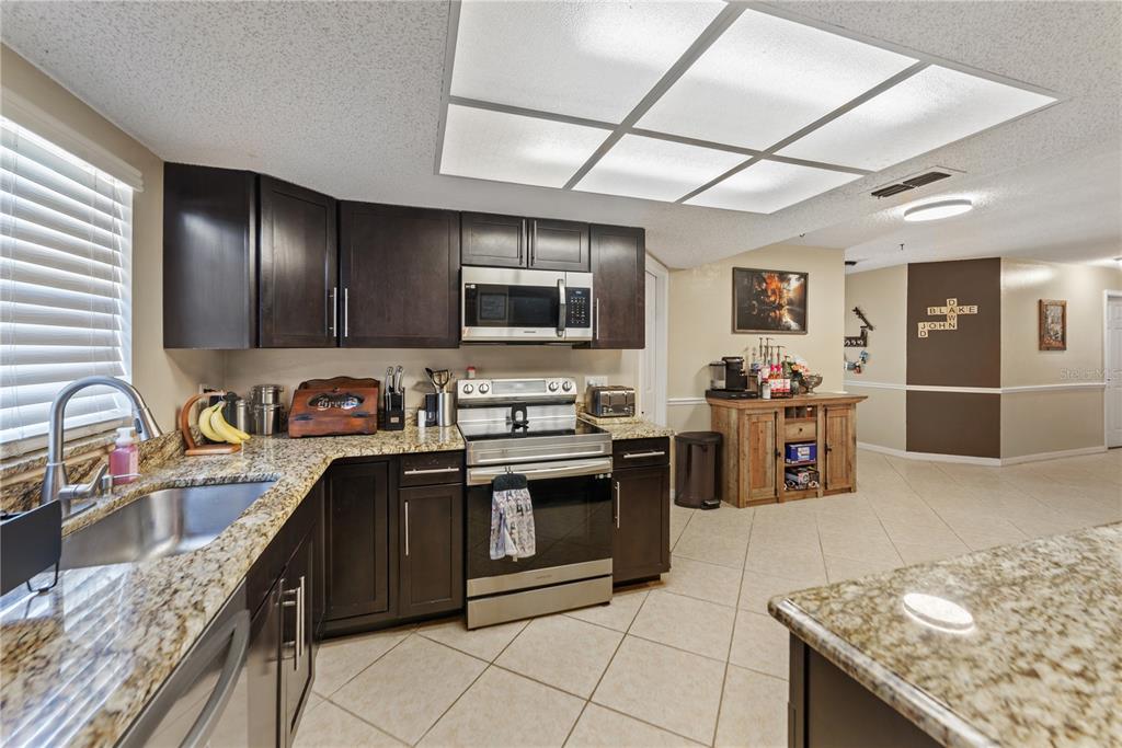 8715 Huntsman Lane Port Richey, FL 34668 - Photo 15 of 54 a kitchen with stainless steel appliances granite countertop a sink stove and refrigerator