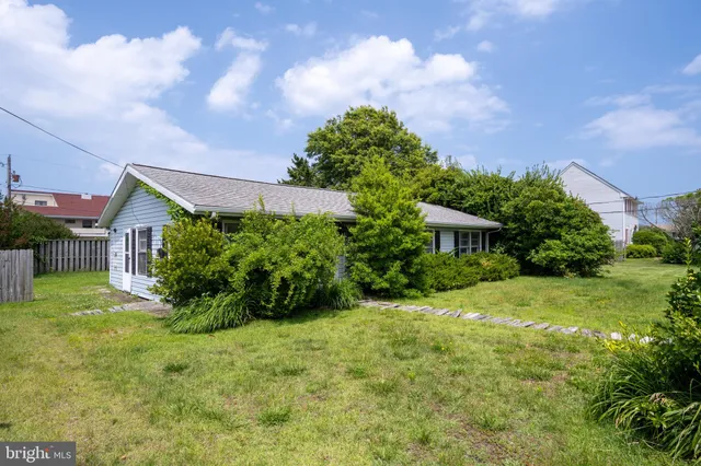 a view of a house with a big yard plants and large trees