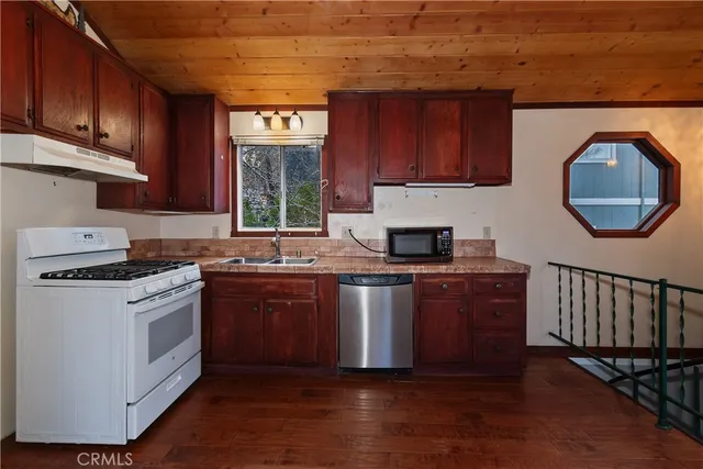 a kitchen with stainless steel appliances granite countertop a stove a sink dishwasher and a microwave oven with cabinets