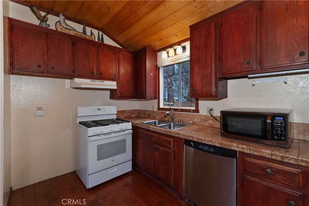 245 Vista Sugarloaf, CA 92386 - Photo 19 of 50 a kitchen with stainless steel appliances granite countertop a stove a sink dishwasher and a microwave oven with cabinets