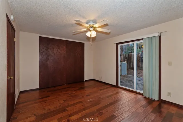 a view of a room with a fan a ceiling fan and wooden floor