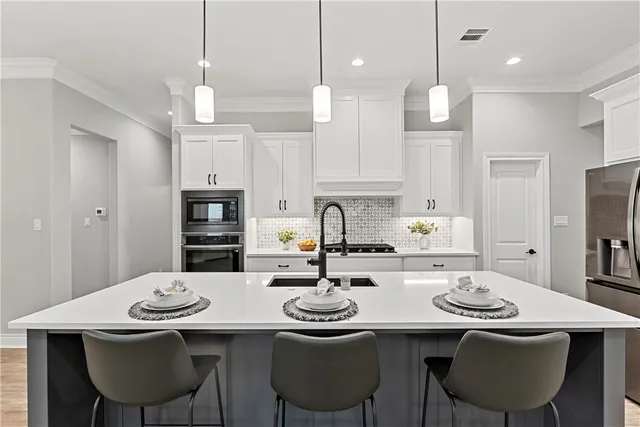 a kitchen with stainless steel appliances a stove a sink a center island and a refrigerator