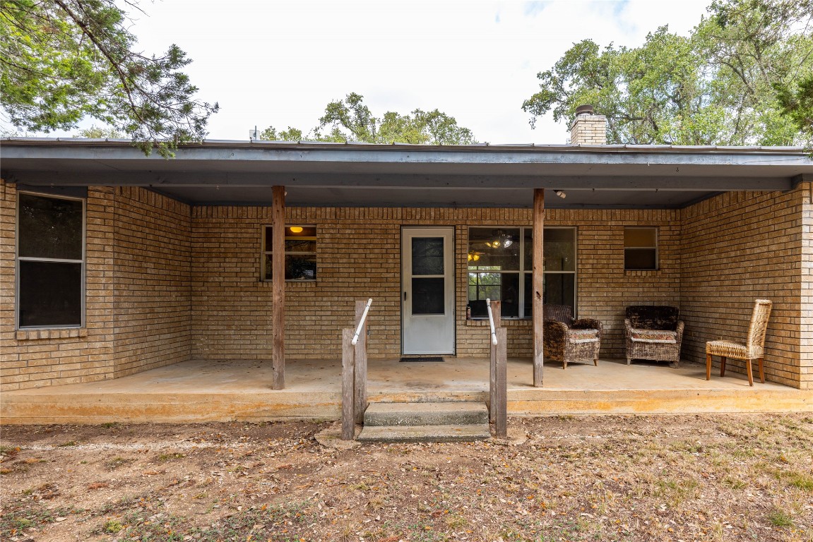 2501 Fischer Store Road Wimberley, TX 78676 - Photo 12 of 37 Doorway to property featuring a chimney, brick siding, and covered porch
