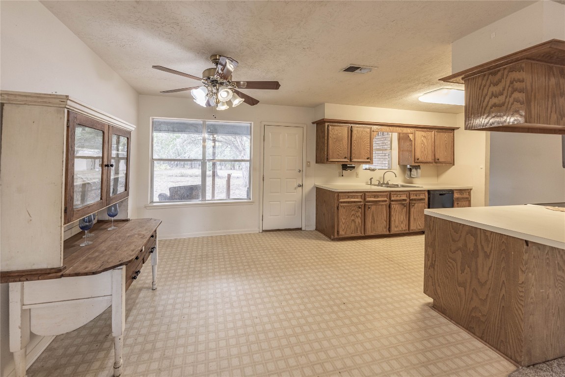 2501 Fischer Store Road Wimberley, TX 78676 - Photo 16 of 37 Kitchen with light countertops, brown cabinets, a textured ceiling, a ceiling fan, and dishwasher