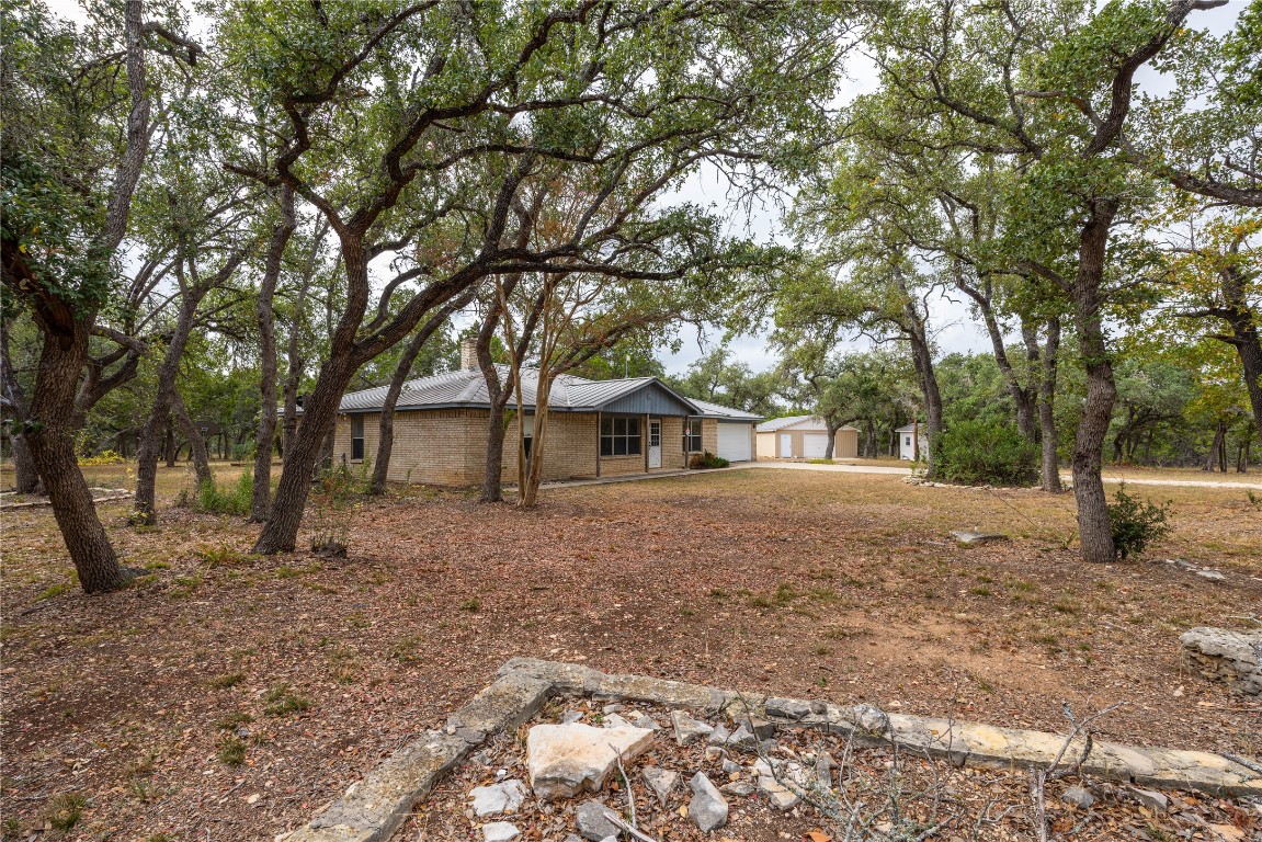 2501 Fischer Store Road Wimberley, TX 78676 - Photo 2 of 37 View of front facade featuring a chimney, a metal roof, and brick siding