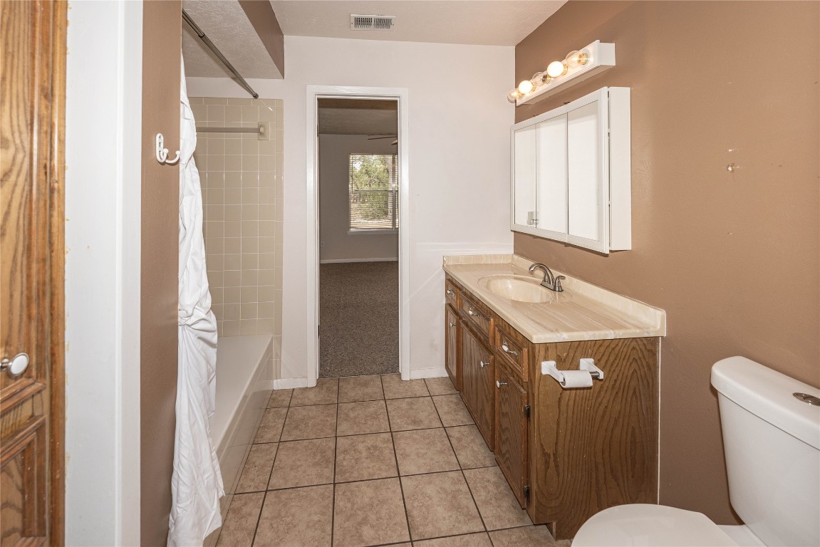 2501 Fischer Store Road Wimberley, TX 78676 - Photo 22 of 37 Bathroom with shower / tub combo with curtain, light tile patterned flooring, and vanity