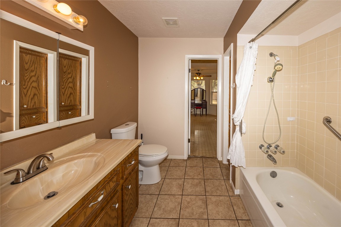 2501 Fischer Store Road Wimberley, TX 78676 - Photo 23 of 37 Bathroom featuring shower / tub combo with curtain, vanity, light tile patterned flooring, a ceiling fan, and a textured ceiling