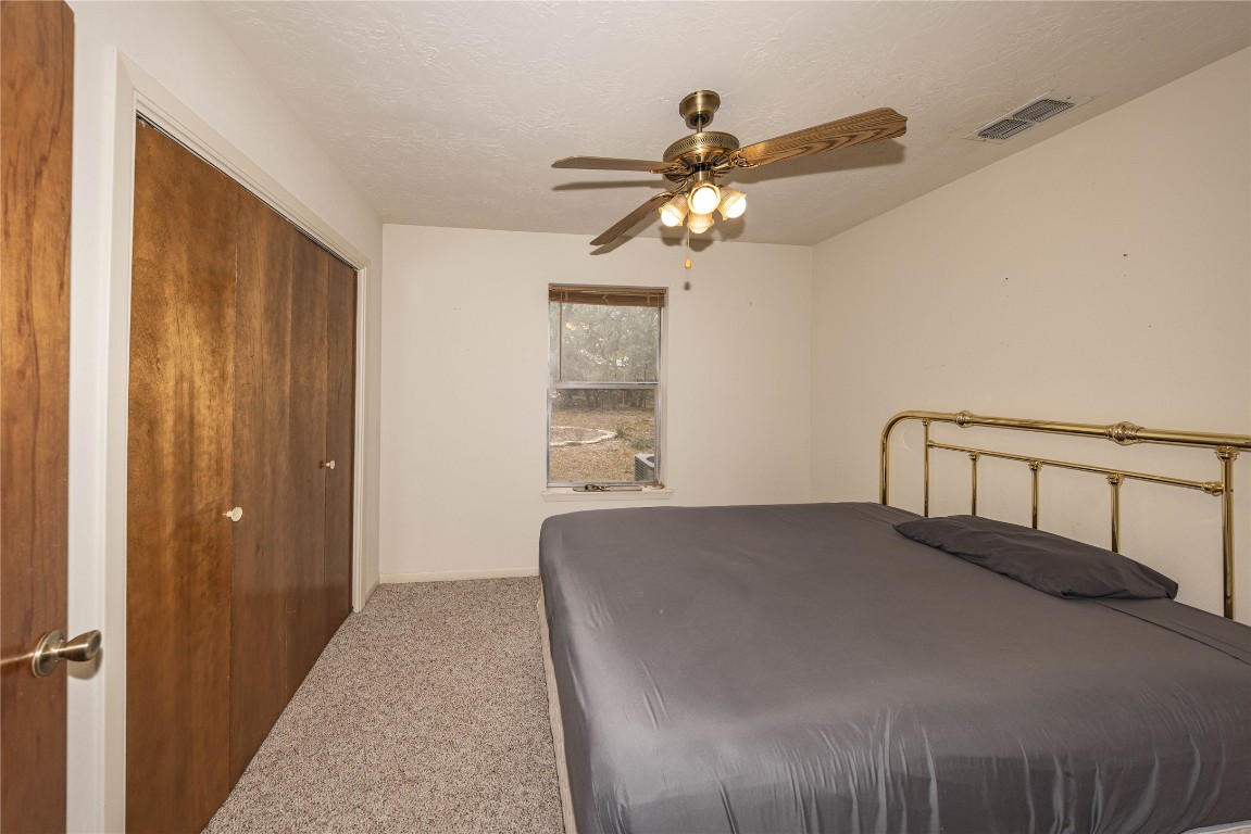 2501 Fischer Store Road Wimberley, TX 78676 - Photo 27 of 37 Bedroom with carpet, a closet, a textured ceiling, and ceiling fan