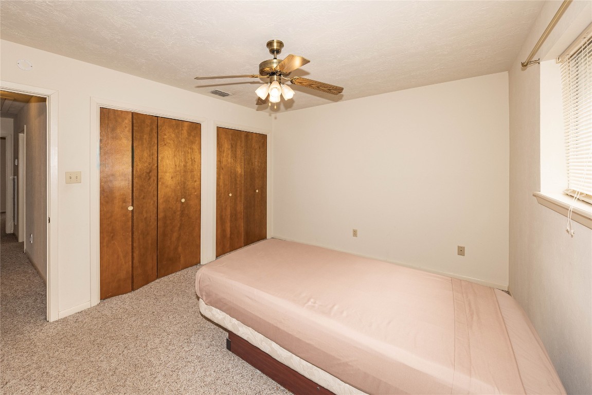 2501 Fischer Store Road Wimberley, TX 78676 - Photo 28 of 37 Unfurnished bedroom featuring multiple closets, light colored carpet, a ceiling fan, and a textured ceiling