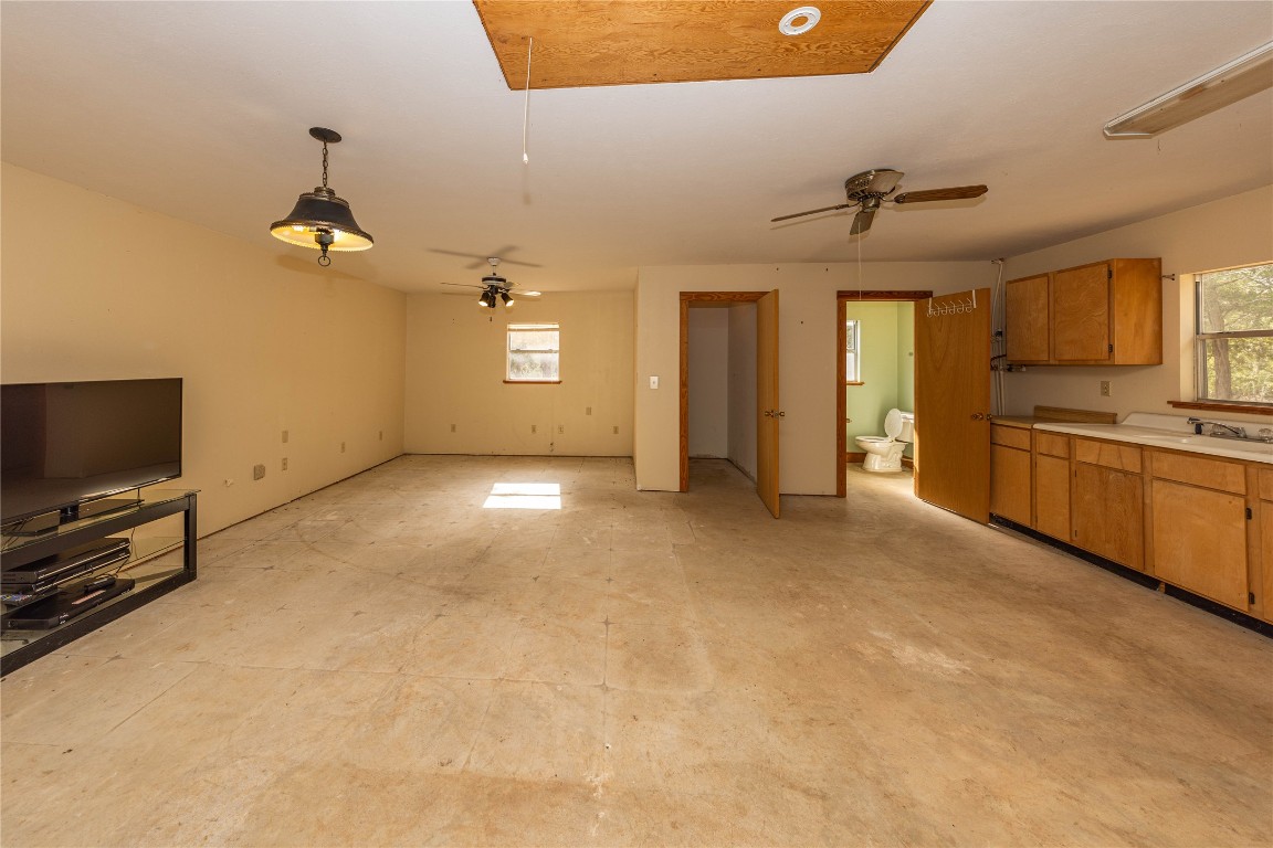 2501 Fischer Store Road Wimberley, TX 78676 - Photo 37 of 37 Ceiling fan, light countertops, brown cabinetry, decorative light fixtures, and open floor plan