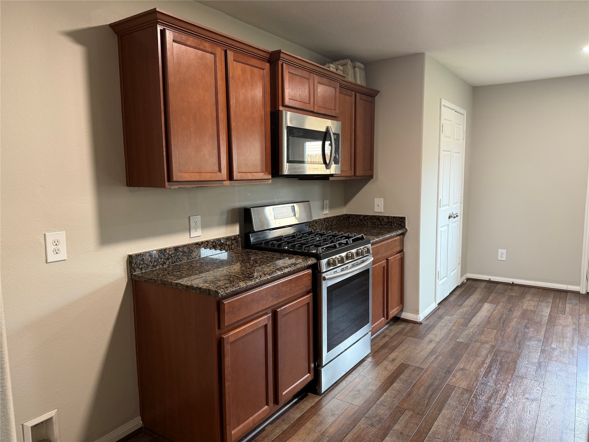 10208 Jewel Court Conroe, TX 77385 - Photo 5 of 23 a kitchen with granite countertop a stove and a wooden floors