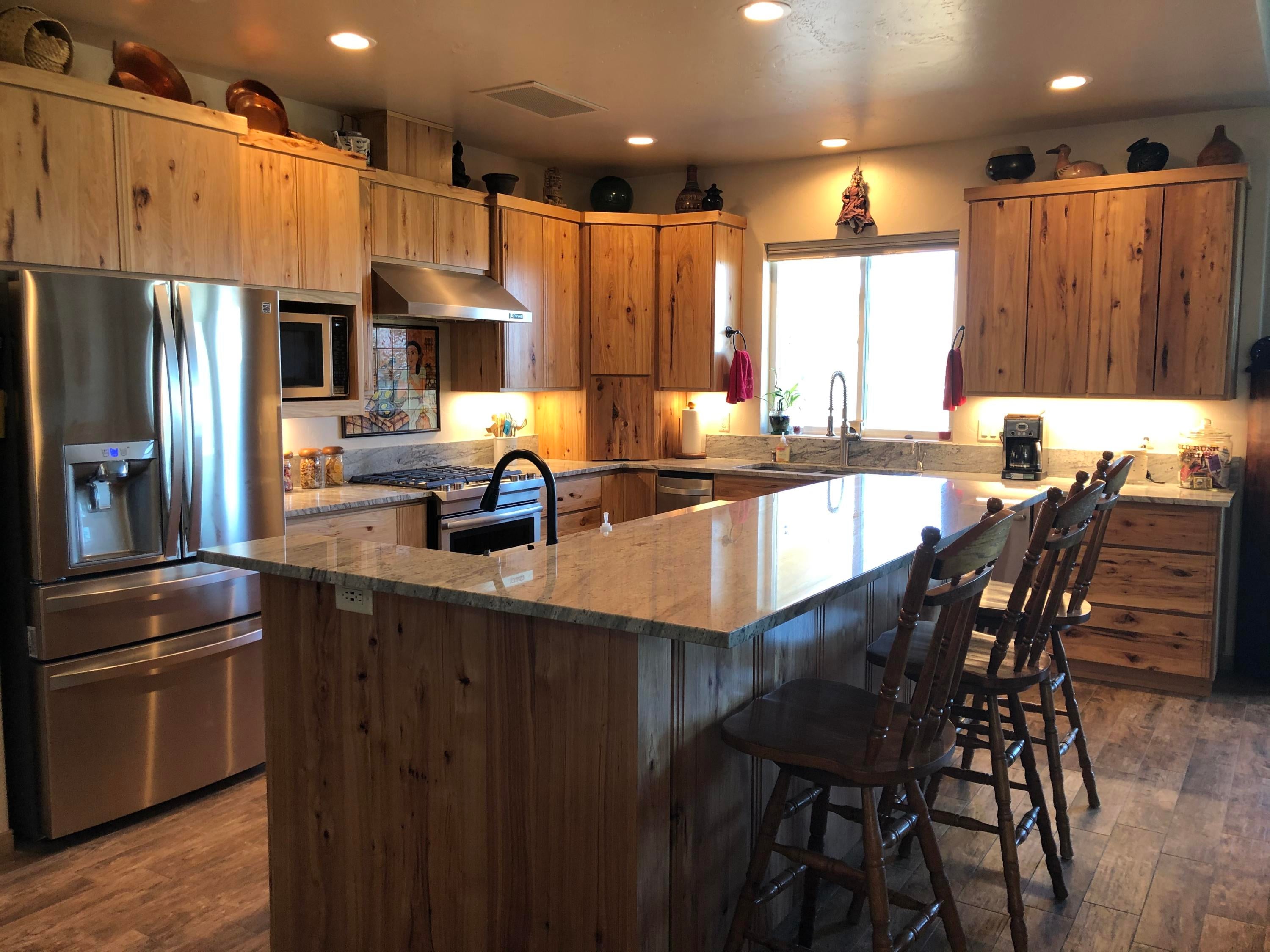 22063 Rickard Road Bend, OR 97702 - Photo 9 of 29 Kitchen has granite breakfast bar, under counter lighting, stainless appliances, super quiet dishwasher, trash compactor, range. Wndow offers mtn. views.
