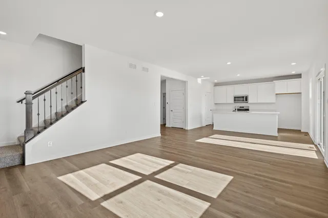 a view of an empty room with wooden floor and stairs