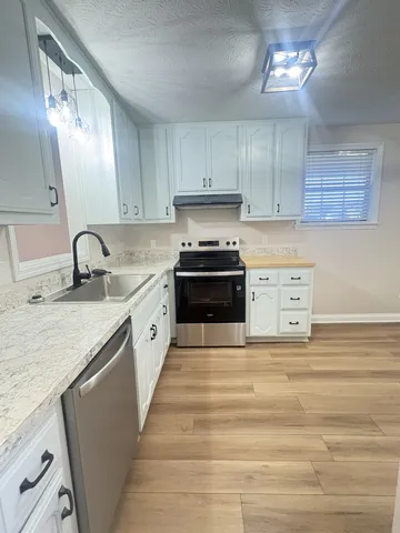 a large kitchen with granite countertop a sink a stove and cabinets
