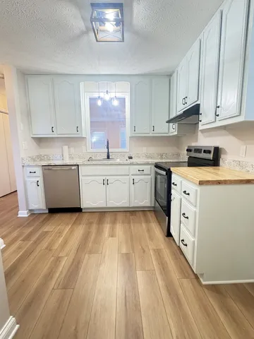a large kitchen with granite countertop a white stove top oven sink and cabinets