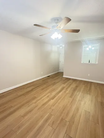 an empty room with wooden floor fan and window