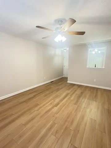 an empty room with wooden floor fan and window