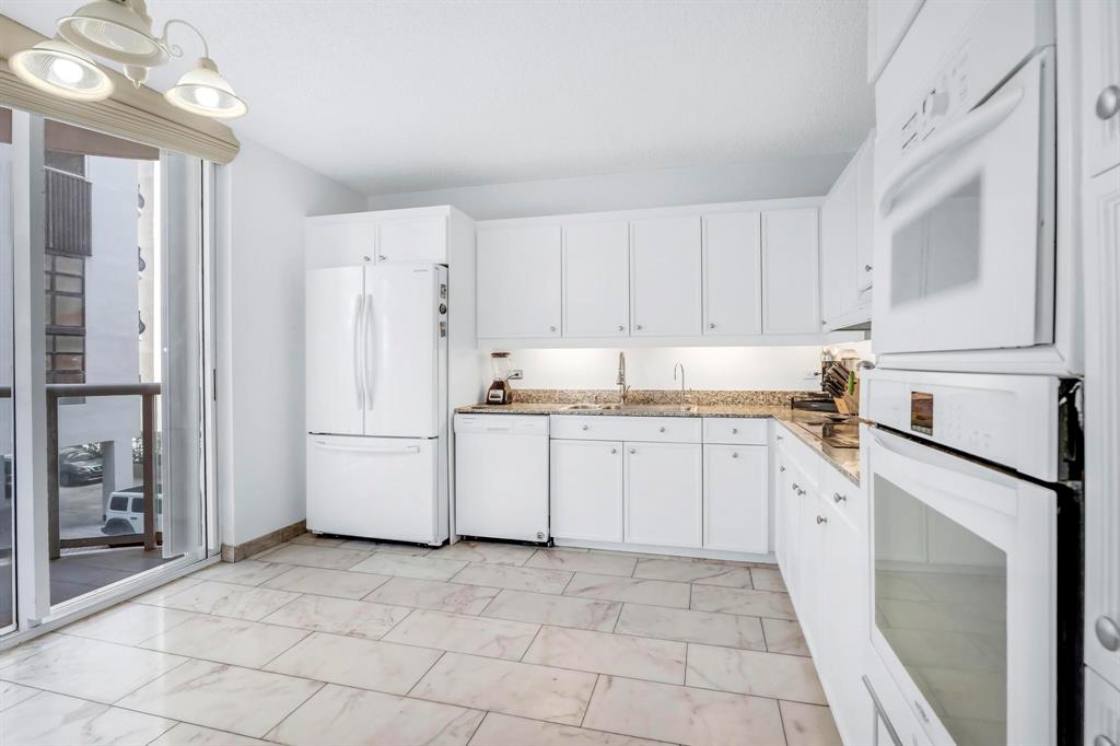 8855 Collins Avenue, Unit 2D Surfside, FL 33154 - Photo 7 of 25 a kitchen with white cabinets and white appliances