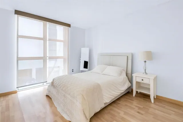 a large bed sitting in a bedroom next to a window and a chair