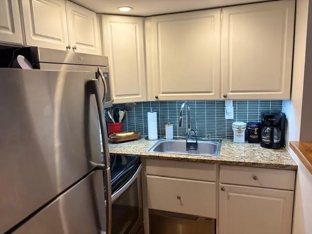 a kitchen with stainless steel appliances granite countertop a refrigerator sink and cabinets