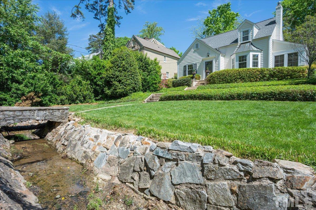 2511 Kenmore Drive Raleigh, NC 27608 - Photo 3 of 34 cross the stone surrounded bridge over enchanted brook to entry. Street parking and sidewalks to stroll in addition to 1 car detached garage access from alley way.